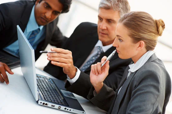 group of people in business attire looking at a laptop