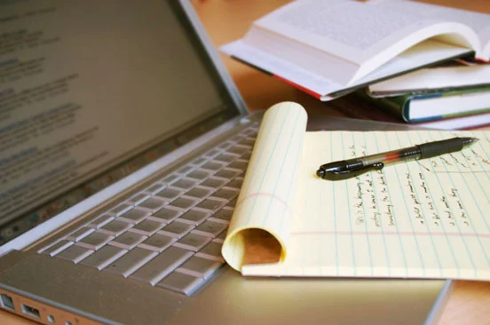 pen and notebook resting on a laptop